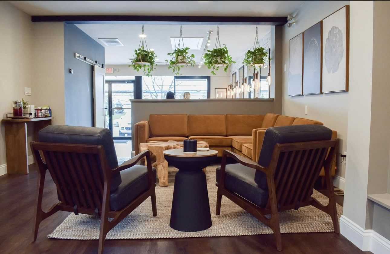 Cozy modern lounge with plants, wood furniture, and a large leather sofa.