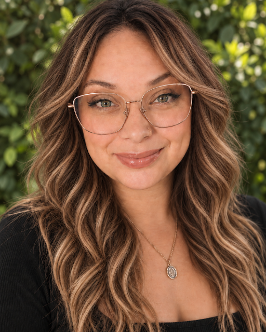 Portrait of Stephanie, a professional hair stylist at Rooted Salon in Allentown, PA, wearing glasses and showcasing highlighted brown hair.